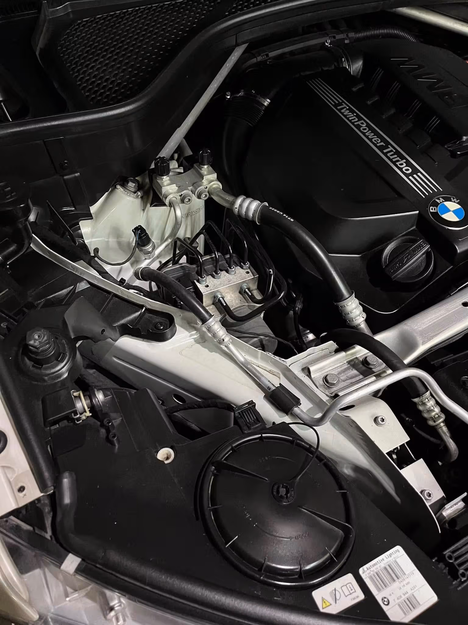 Close-up of a BMW TwinPower Turbo engine compartment with visible pipes and engine cover.