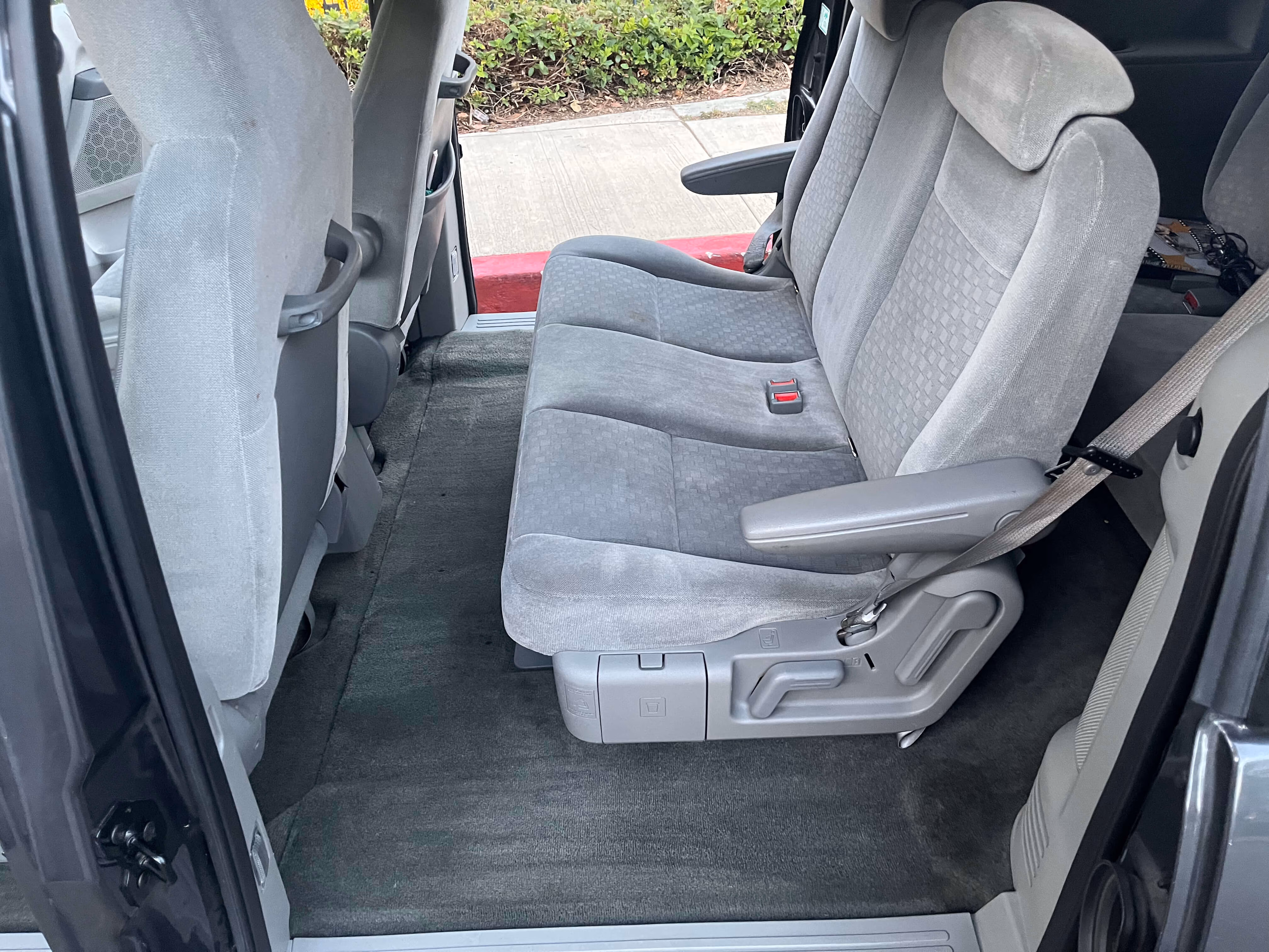 Gray fabric middle row seats in a vehicle with visible armrest and seatbelt.