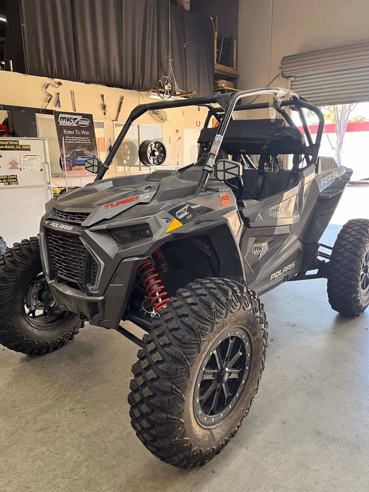 Black Polaris Turbo S off-road vehicle with large tires inside a garage.