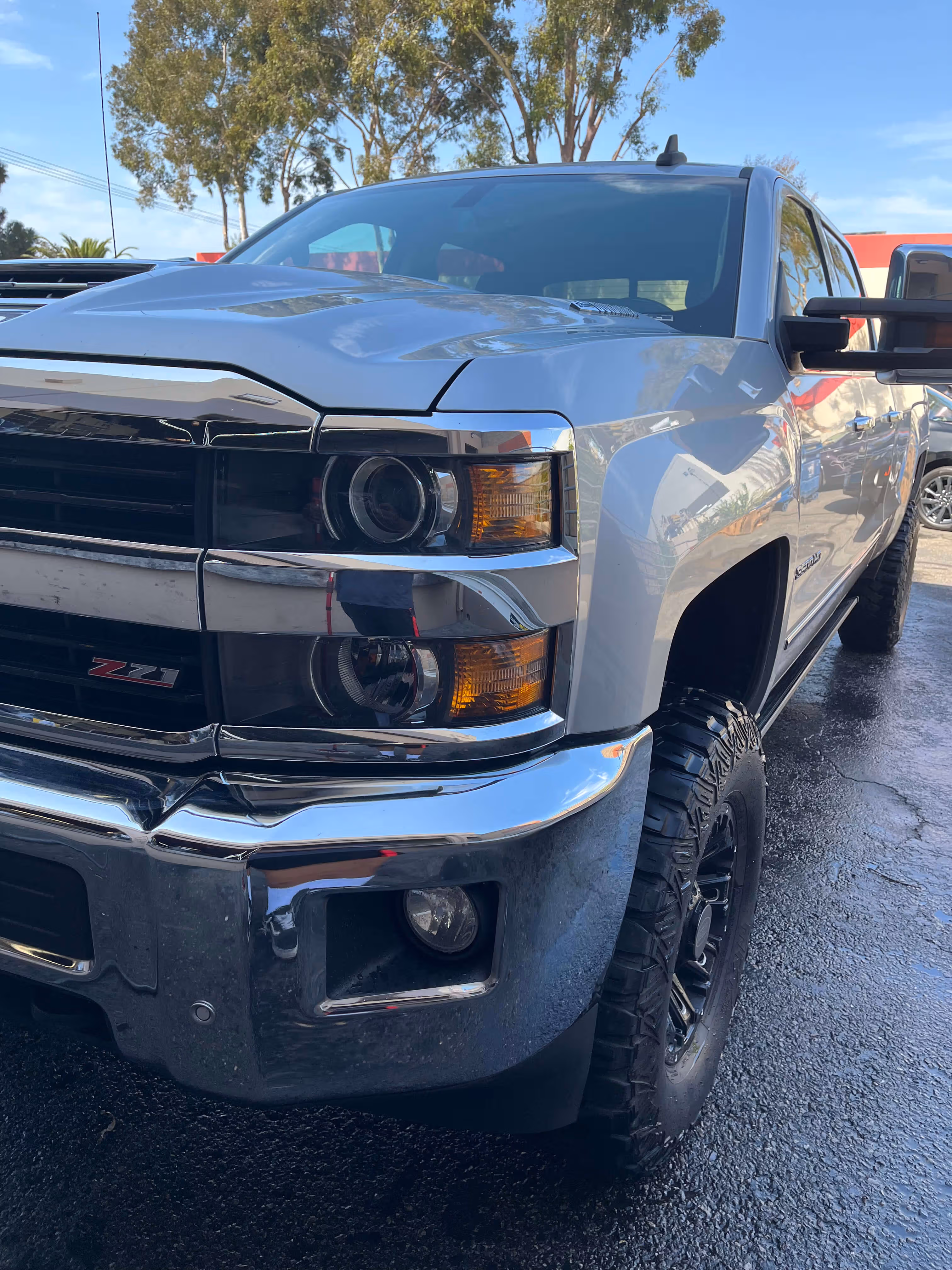 Front side view of a silver Chevrolet Z71 truck with black off-road tires and chrome bumper.