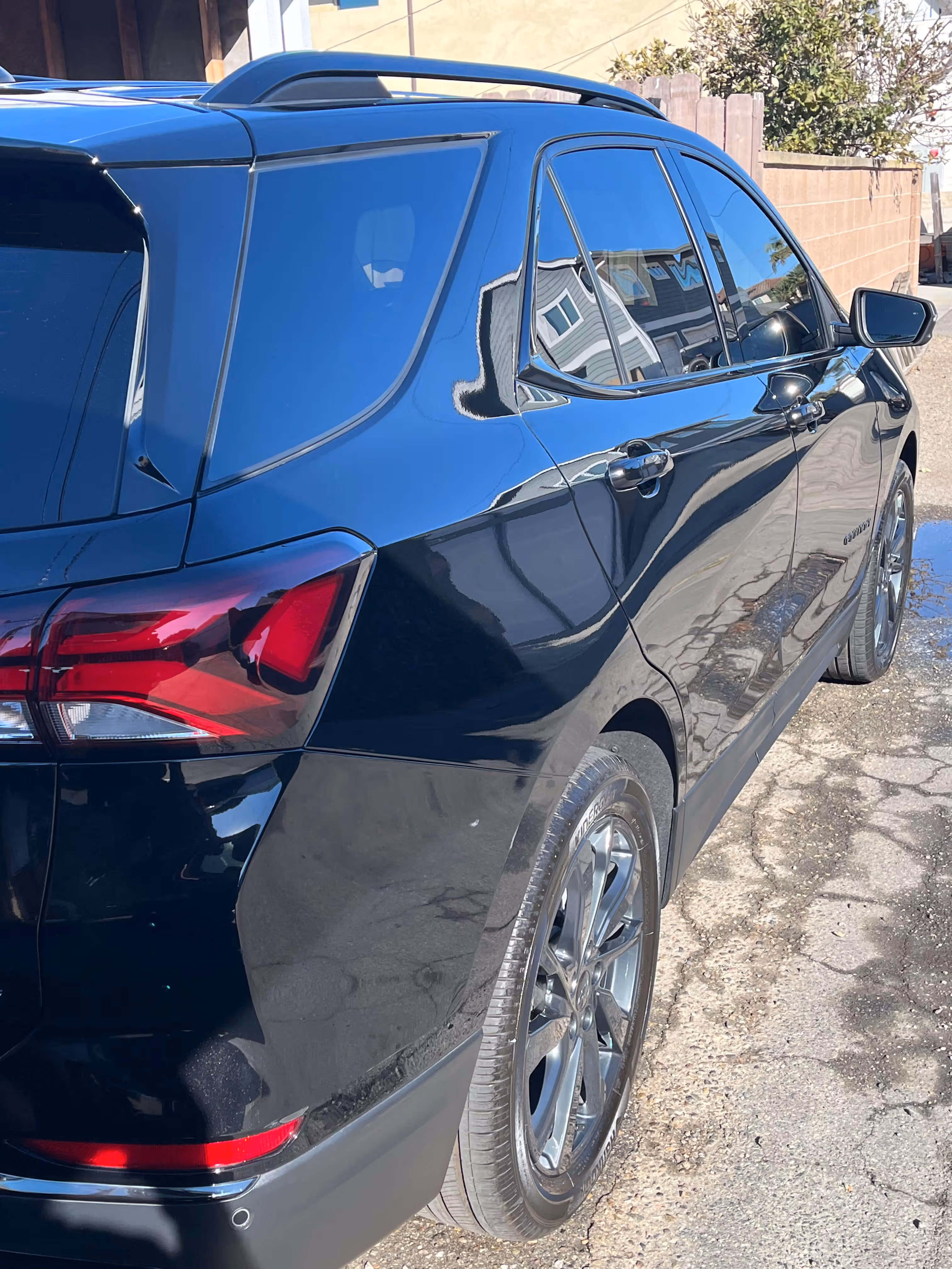 Black SUV parked on a cracked pavement with tinted windows and visible rear taillight.