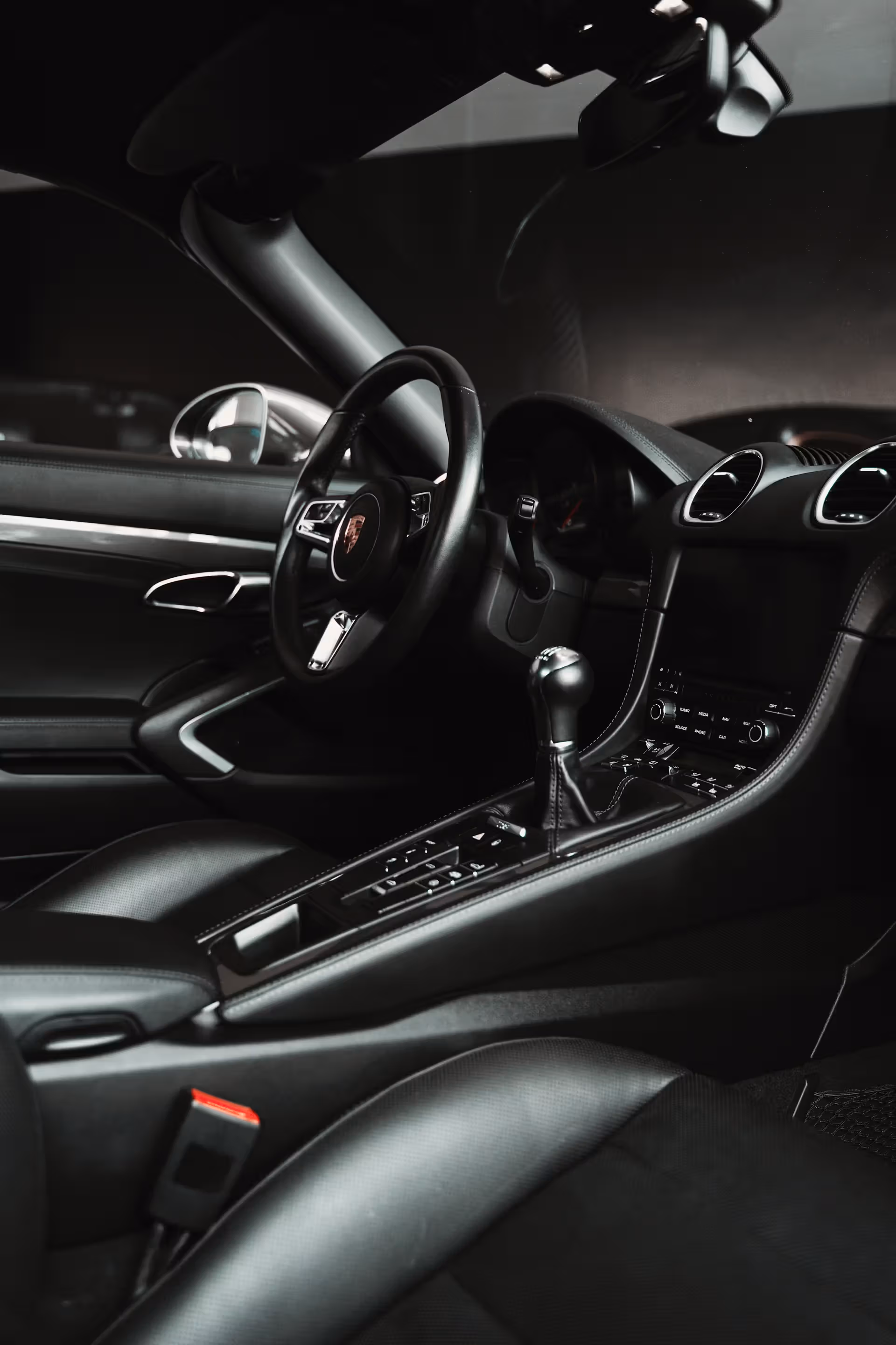 Interior of a luxury sports car showing the steering wheel, manual gear shift, and dashboard controls.